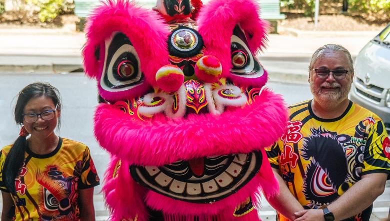Lion dancers standing on either side of a lion mask at a Lunar New Year event
