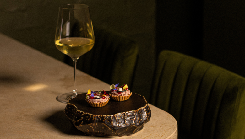 Lab grown cultured Japanese quail parfait presented on a plate in a restaurant along with a glass of wine