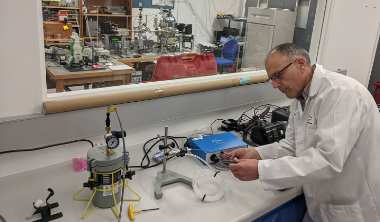 A metrologist sets up equipment for testing face masks.