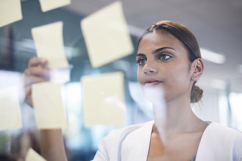 Woman picking up an idea note from a board