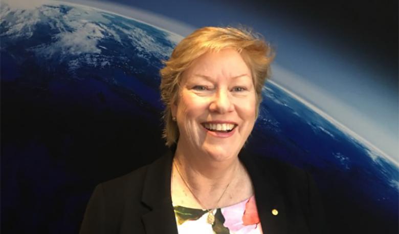 Image of Dr Clark in front of a picture of Earth Image of Dr Clark in front of a picture of Earth
