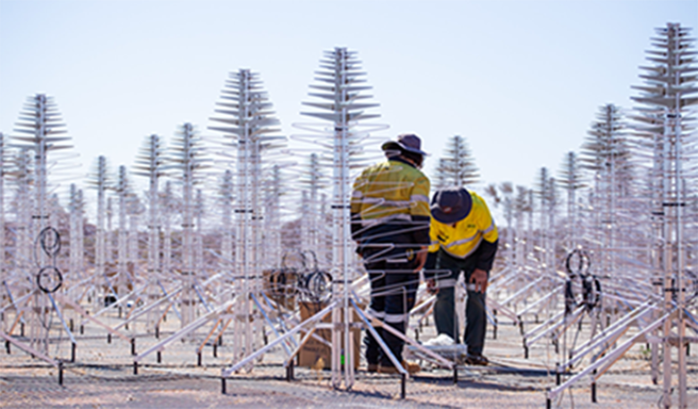 Two engineers inspect antenna design outside.