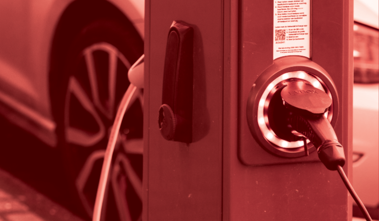 Photo of an electric vehicle charging station in front of a car. There is a red colour overlay.