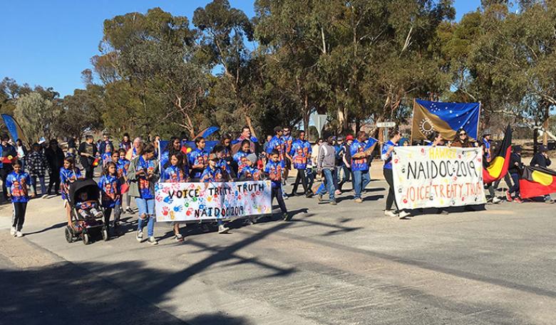 Adults and children carry banners as they march through Hawker during NAIDOC Week.