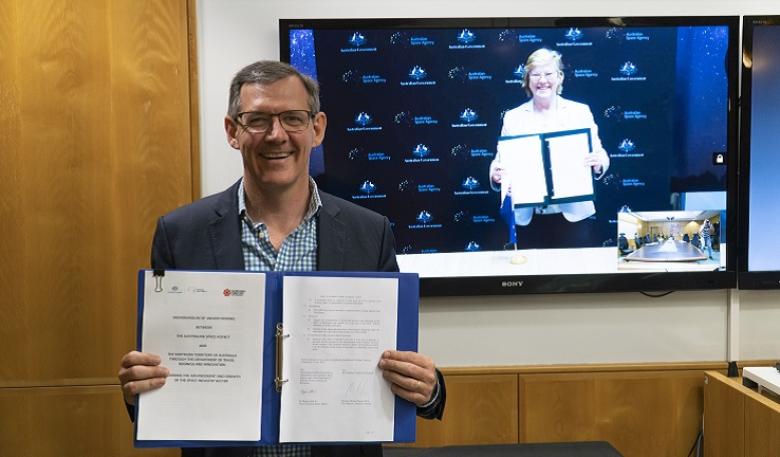 Chief Minister of the Northern Territory Hon Michael Gunner and Dr Megan Clark AC Northern Territory Chief Minister holds up MOU on a virtual call with Australian Space Agency Head.