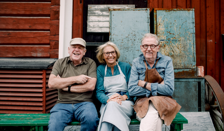 Three people sitting on a bench in front of a shop