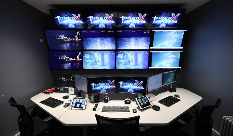 A bank of computer screens and three computers on a table