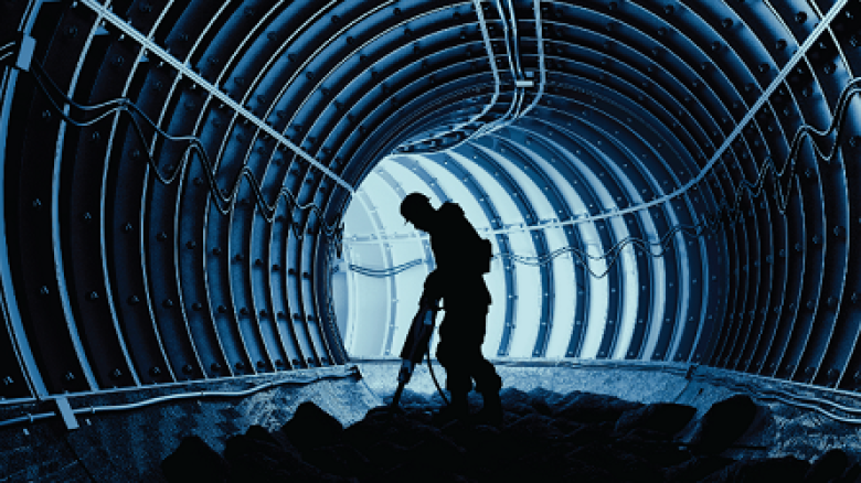 A man using a jackhammer in a tunnel