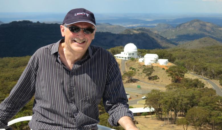 Astronomer-at-large, Fred Watson, with the Siding Spring Observatory at a distance in the background. Astronomer-at-large, Fred Watson, poses for a photo with the Siding Spring Observatory at a distance in the background.
