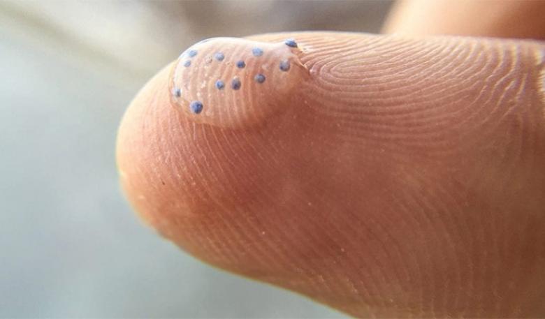 Microbeads of plastic suspended in liquid on a person’s finger