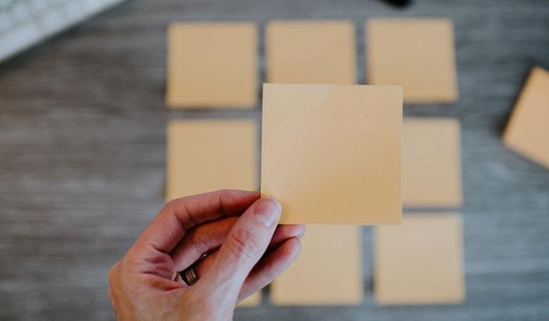Photo of a hand holding a blank post-it note