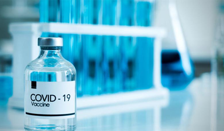 A glass vial with the words COVID-19 Vaccine written on it
