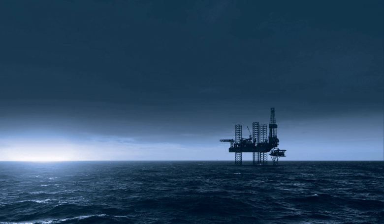 A dark ocean landscape image with an oil rig in the horizon.