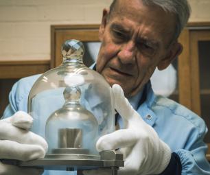 Photo of a man examining a metal weight under glass domes.