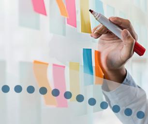 Close up of hand holding pen and sticky notes on wall