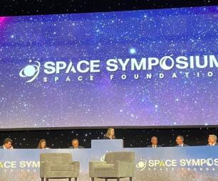 2023 space symposium stage with speakers sitting in a row.