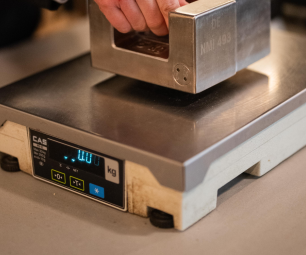 Trade Measurement Officer testing a NAWI (non-automatic weighing instrument) in use for trade. 