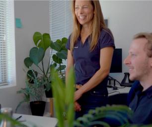 Dr Katherine Giles and a colleague wearing their company’s uniform appear in front of a computer,