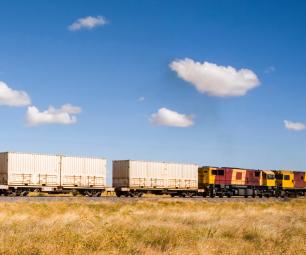 Train carrying shipping containers in country area 