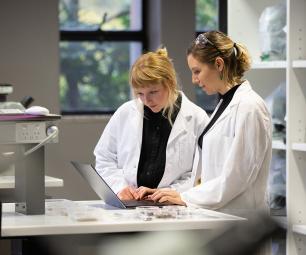 Photo of 2 scientist looking at a laptop in a laboratory