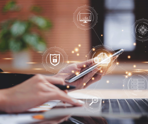 Photo of a person on their laptop holding a mobile phone. Superimposed with icons representing different technologies.