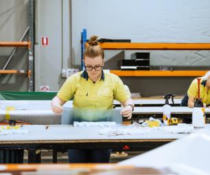 Photo of a woman working with moulded plastic and signage in an industrial warehouse
