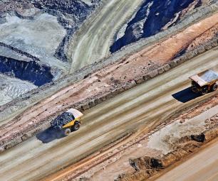 Two mining trucks drive along a road.
