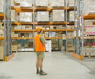 Worker in high-vis vest taking stock of supplies in a warehouse