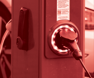Photo of an electric vehicle charging station in front of a car. There is a red colour overlay.
