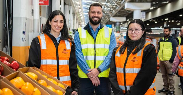 Three trade measurement inspectors standing in a fruit and vegetable market