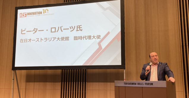 Man stands at lectern with microphone and screen behind