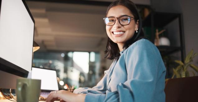 Young woman sitting at a computer smiling