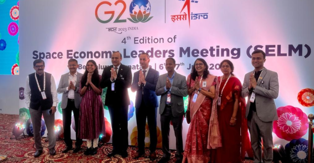 A group of delegates people posing for a photo in front of a media wall at the G20 space meeting in Bengaluru, India. 