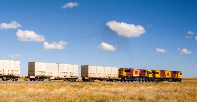 Train carrying shipping containers in country area 