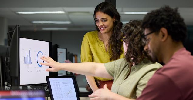 Group of diverse people looking at data on a computer screen. 