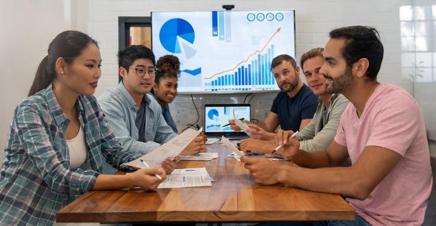 Group of diverse people sitting around a table talking. 