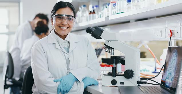 Female scientist dressed in a lab coat. In a modern laboratory with microscope.