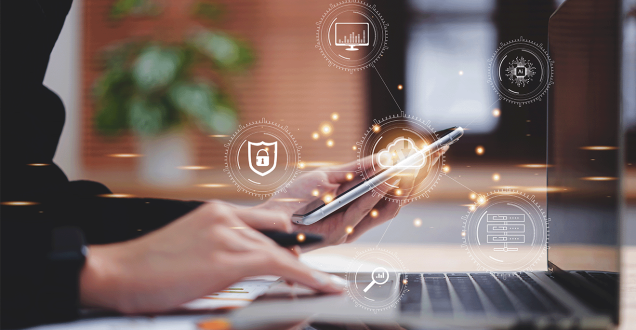 Photo of a person on their laptop holding a mobile phone. Superimposed with icons representing different technologies.