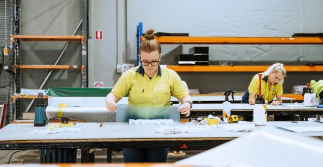 Photo of a woman working with moulded plastic and signage in an industrial warehouse