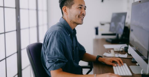 Close up photo of an office worker sitting at their desk and working at a computer