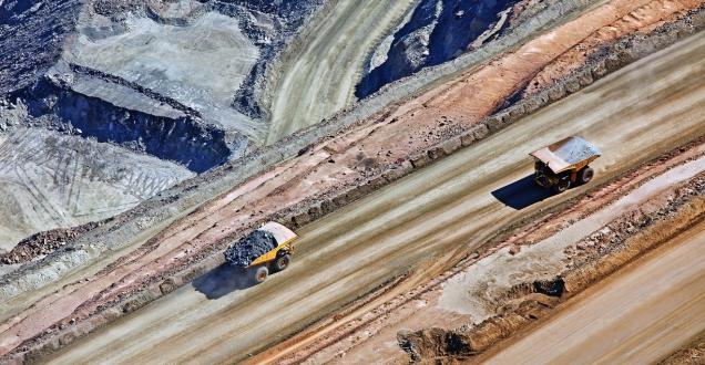 Two mining trucks drive along a road.