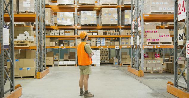 Worker in high-vis vest taking stock of supplies in a warehouse