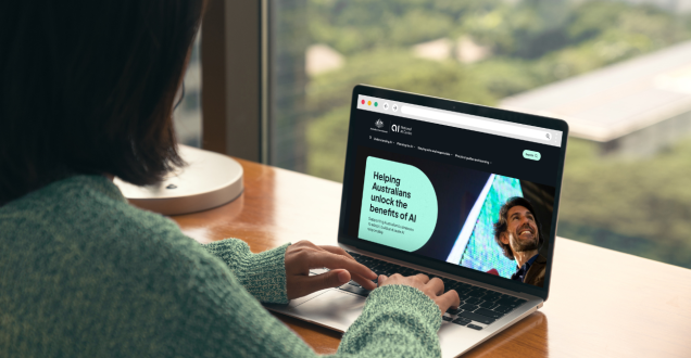 Person typing on a laptop with the screen showing the home page of the Ai.gov.au website