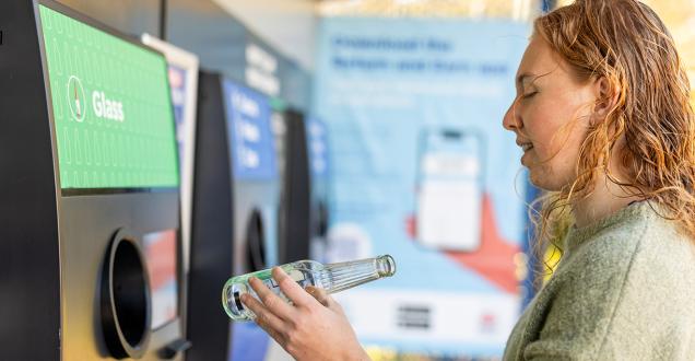 Young woman using a bottle recycling machine. 