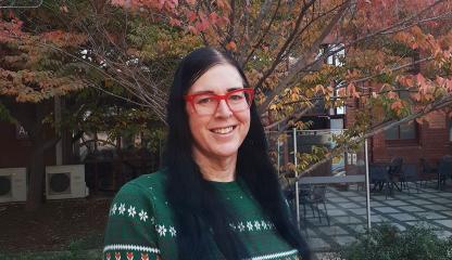 Photo of Deanne Fisher standing in front of an autumn tree on a university campus