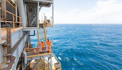 2 workers in fluro orange  on an oil rig in the ocean