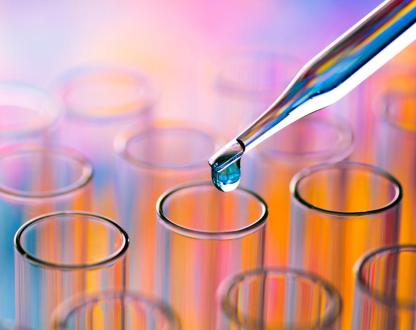 A pipette dropping blue liquid into test tubes