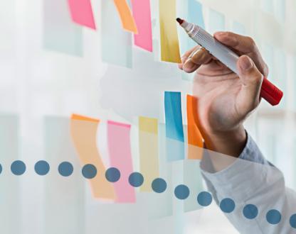 Close up of hand holding pen and sticky notes on wall