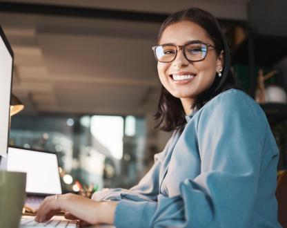 Young woman sitting at a computer smiling