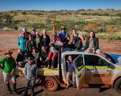 A team of people on a dual-cab ute in the Australian Outback.